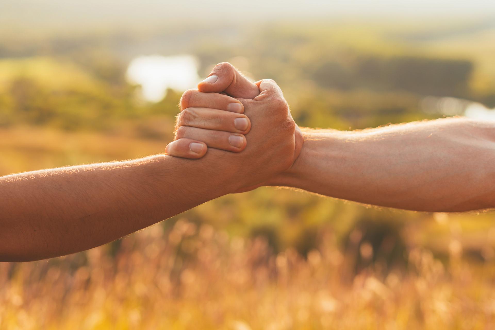 Two strong hands are holding one by another for help and cooperation.