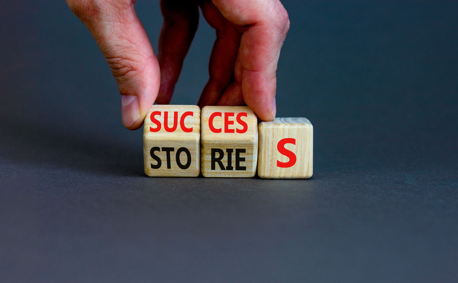 Success stories symbol. Businessman turns wooden cubes and changes the word stories to success. Beautiful grey table, grey background, copy space. Business success stories story concept.